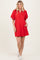 woman wearing a red short sleeve polo dress with a zip neckline and puff sleeves, standing with one hand in the pocket