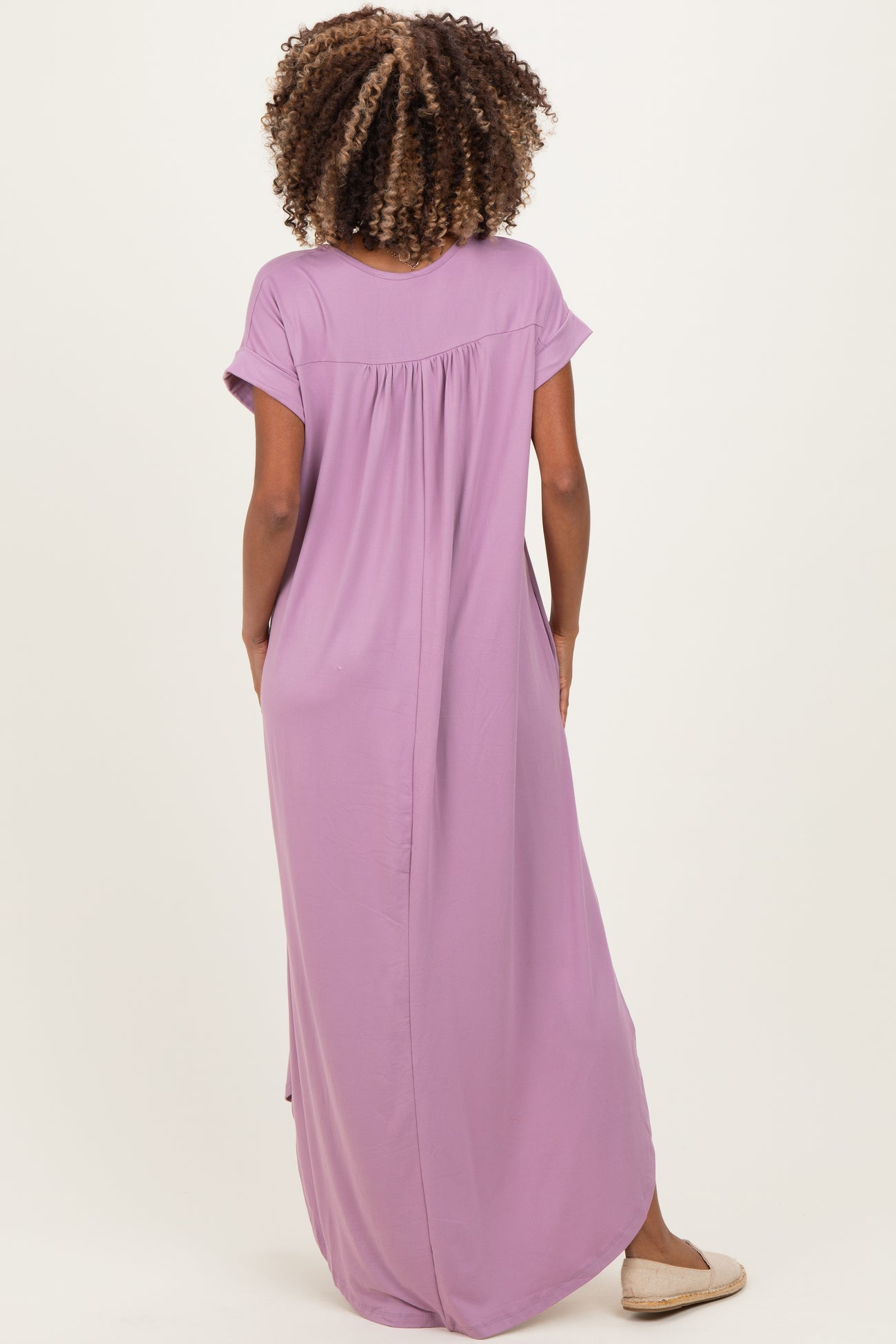 woman wearing a lavender maternity maxi dress with short sleeves and a relaxed fit, showing the back view
