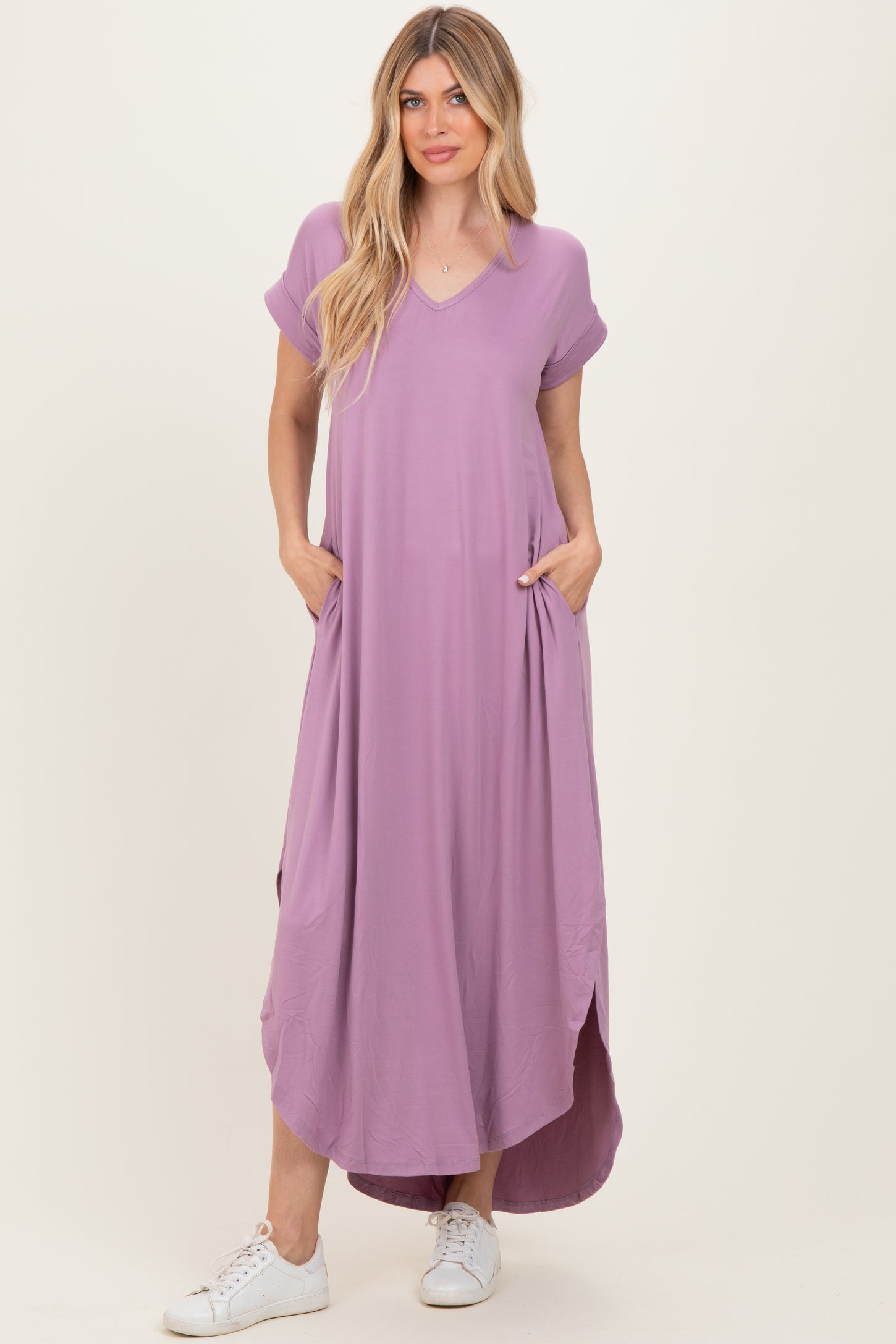 woman wearing a lavender short sleeve maxi dress with pockets and side slits, paired with white sneakers