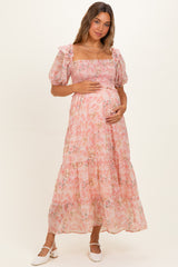 woman wearing a pink floral off-shoulder maternity dress with puff sleeves and a baby bump