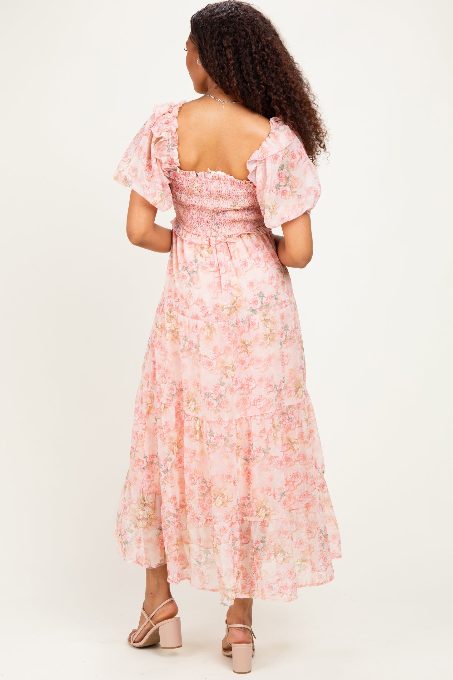 woman wearing a pink floral smocked maxi dress with ruffled sleeves and open back