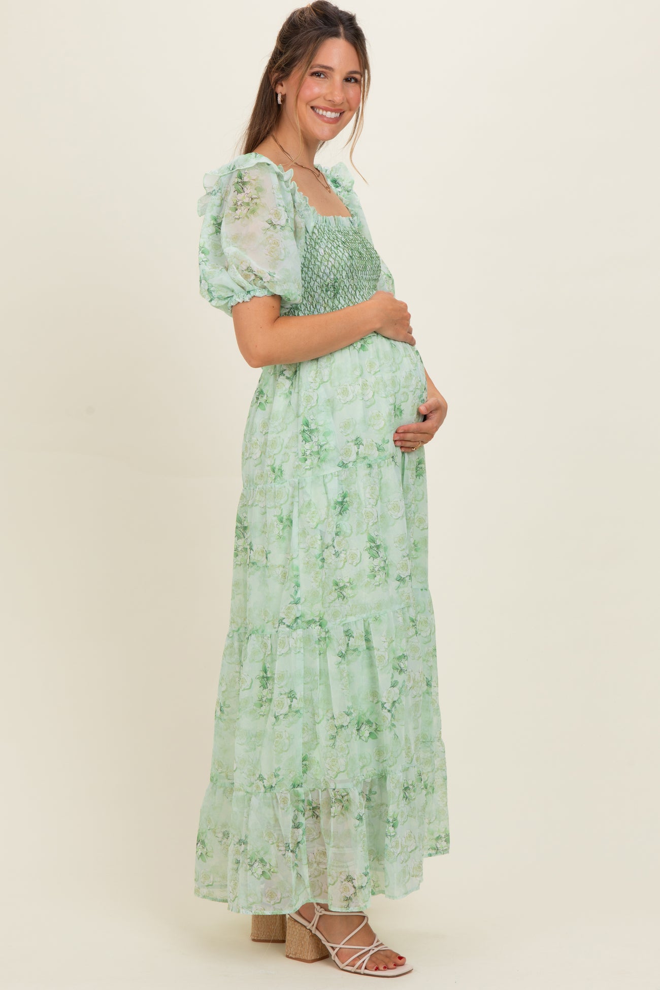 woman wearing a green floral maternity maxi dress with smocked bodice and puff sleeves, showing baby bump