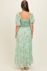 woman wearing a green floral maternity dress with puff sleeves and a smocked bodice, showing the back view