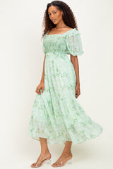 woman wearing a green floral midi dress with puff sleeves and a smocked bodice