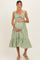 woman wearing a green and white gingham maternity dress with a ruffled hem and holding her baby bump