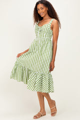 woman wearing a green and white gingham midi dress with a ruffled hem and buttons, standing with a playful pose