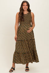 woman wearing a black floral maternity maxi dress with tiered ruffles and holding her baby bump
