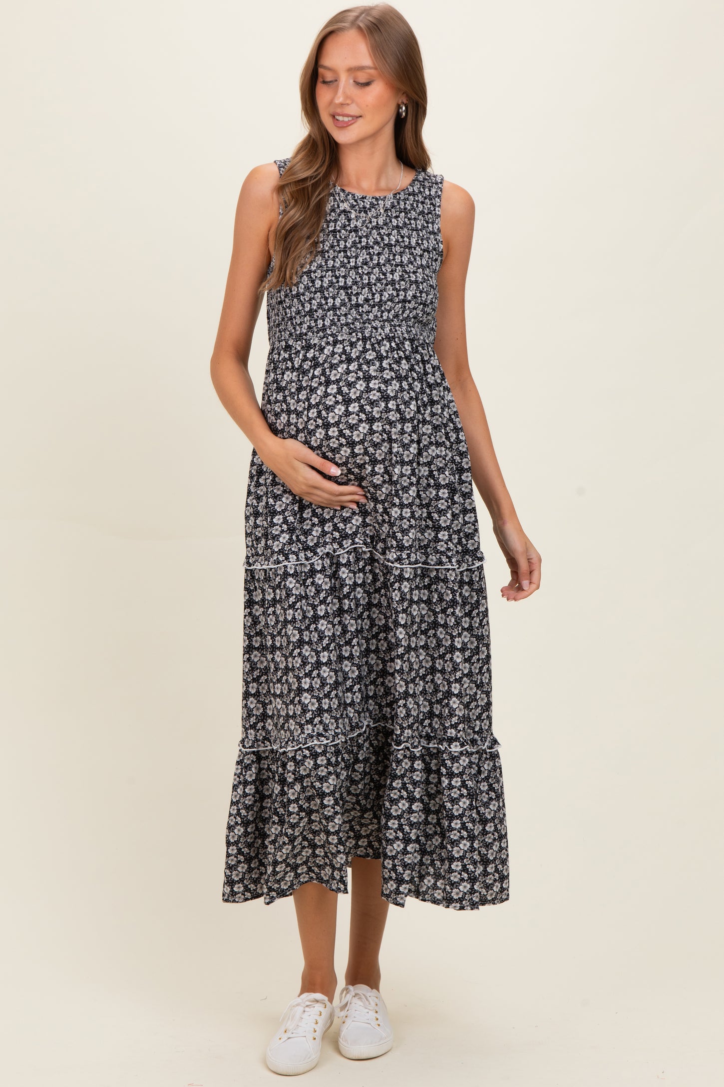 woman wearing a black floral maternity maxi dress with tiered layers and holding her baby bump