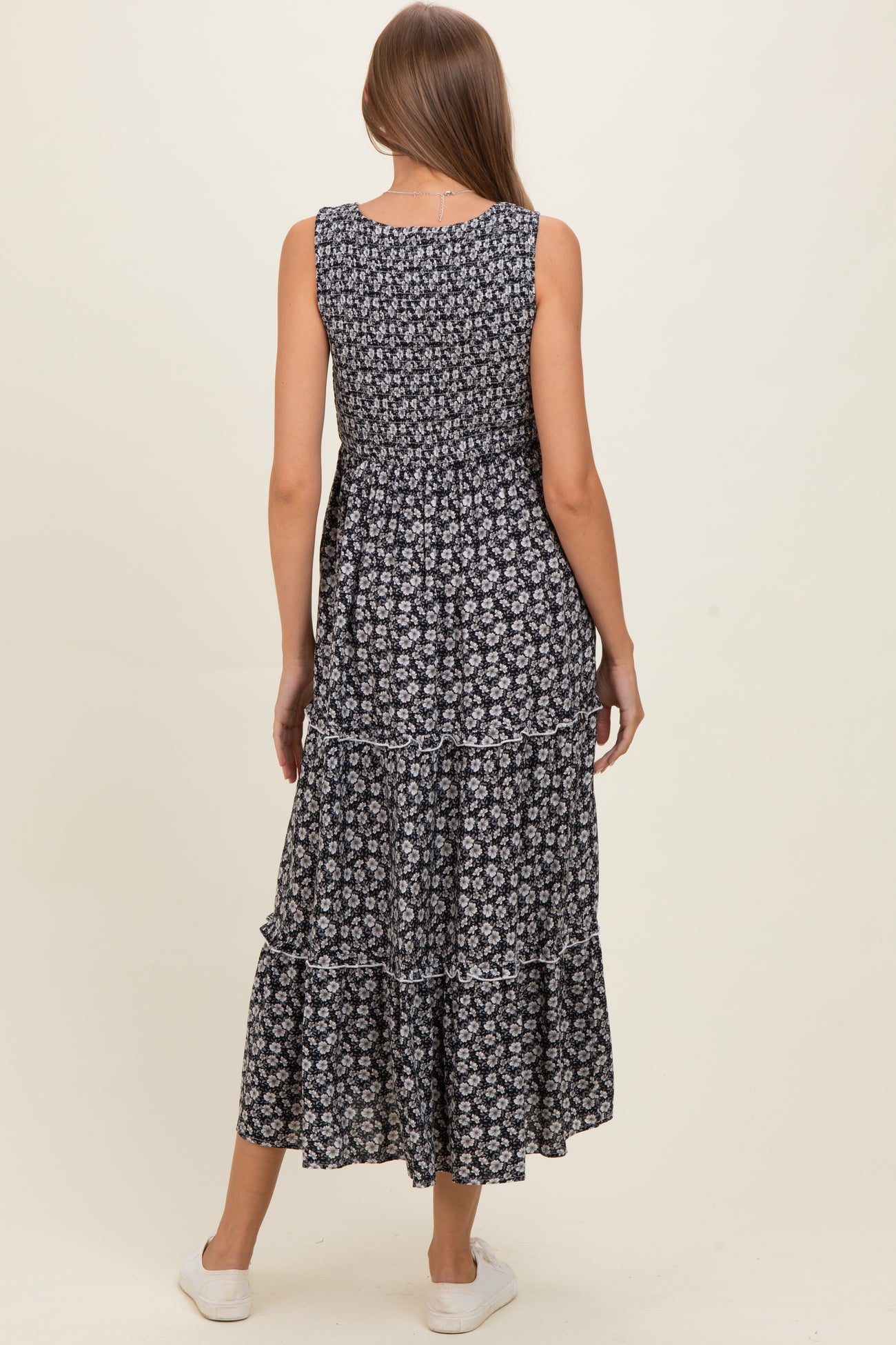 woman wearing a navy blue floral maternity maxi dress with tiered ruffles and a smocked back detail