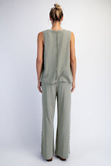 woman wearing a back view of a green sleeveless top and matching wide-leg pants with button details
