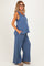woman wearing a blue maternity tank top and matching wide-leg pants, with a visible baby bump and pockets on the pants