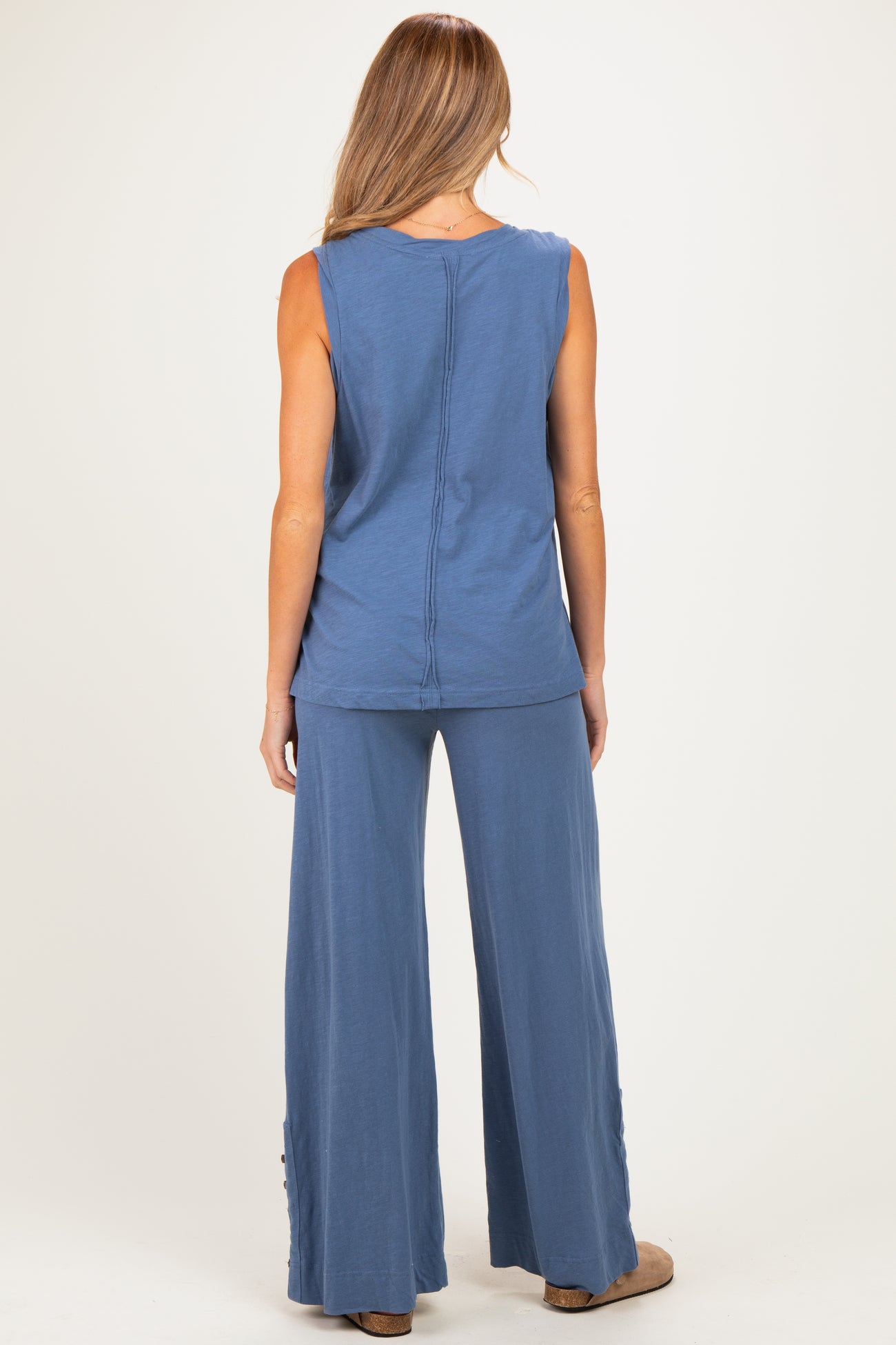 woman wearing a blue maternity top and matching wide-leg pants, showing a relaxed fit and back view