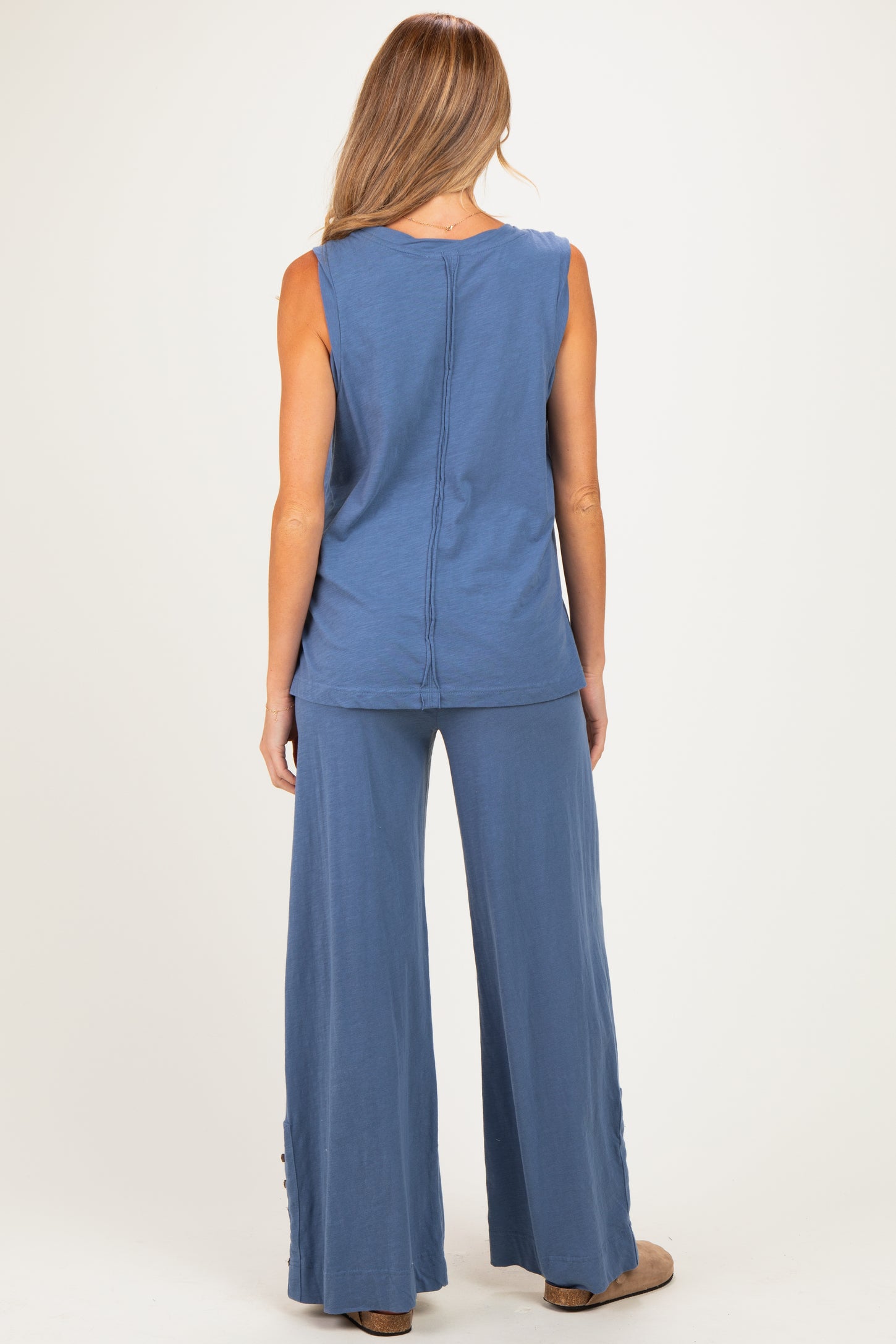 woman wearing a blue maternity top and matching wide-leg pants, showing a relaxed fit and back view