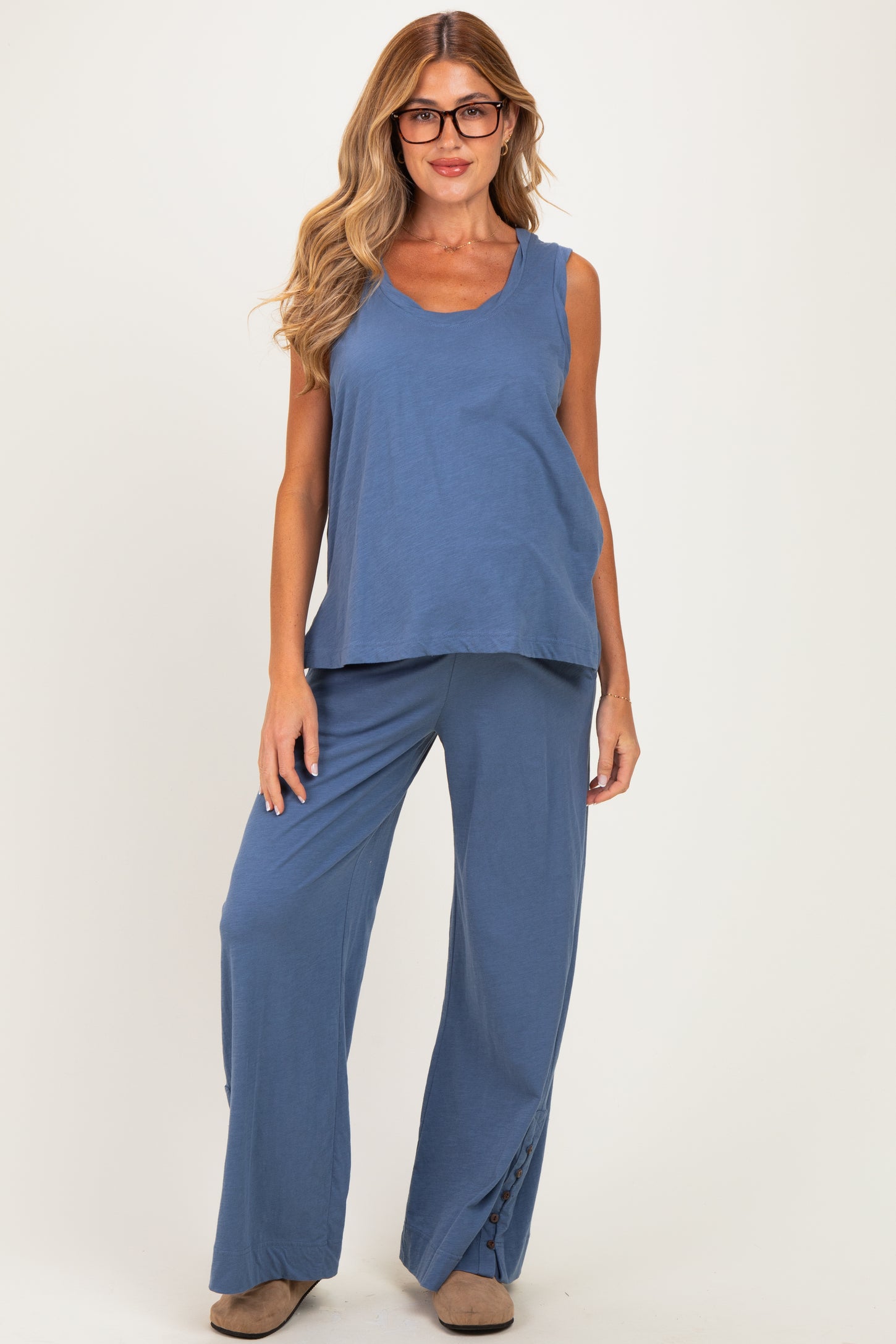 woman wearing a blue sleeveless maternity top and matching wide-leg pants with side slits