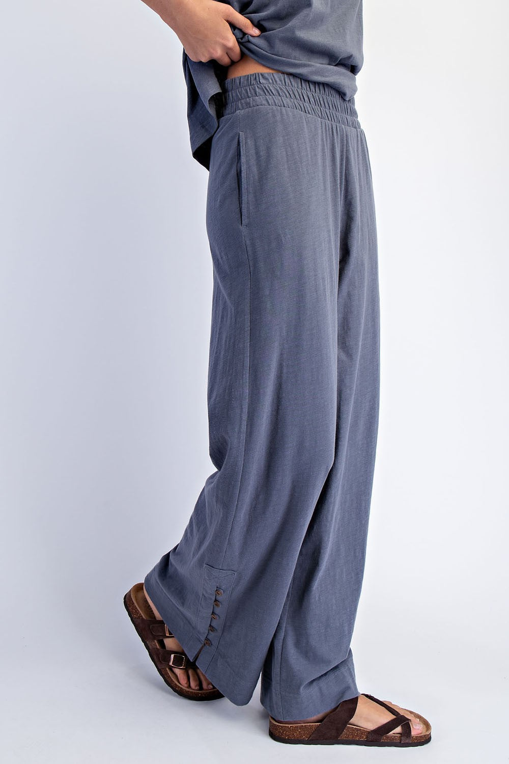 woman wearing gray wide-leg pants with an elastic waistband and side pockets, paired with brown sandals