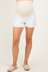 woman wearing white maternity denim shorts with a beige over-the-bump waistband and slip-on shoes