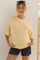 woman wearing a light yellow oversized maternity sweater with short sleeves and distressed black shorts