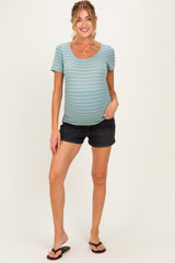 woman wearing a striped light blue maternity top and black shorts, showcasing her baby bump