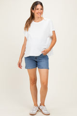 woman wearing a white short sleeve maternity top and denim shorts, showing her baby bump