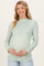 woman wearing a light green floral long sleeve maternity top and holding her baby bump