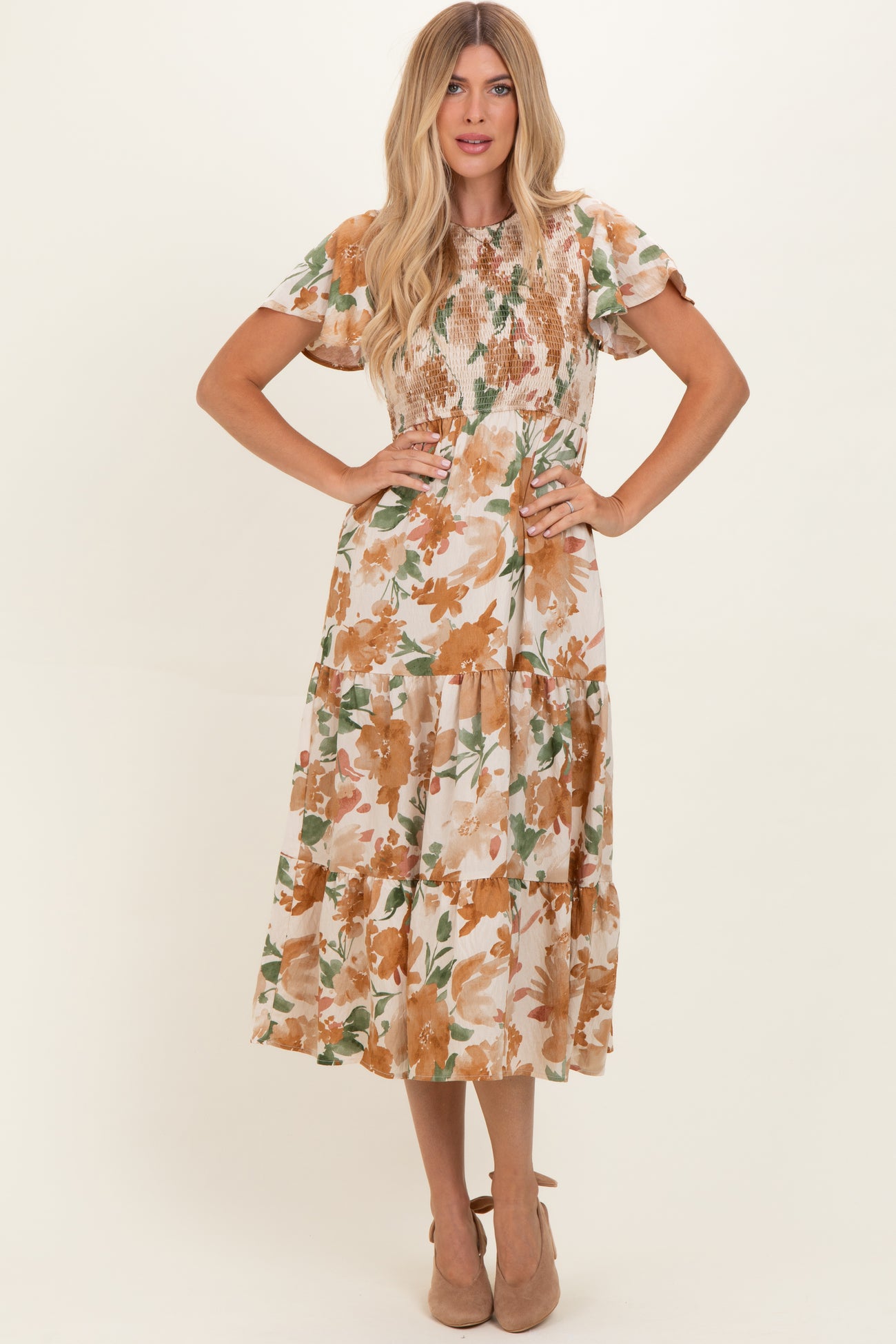 woman wearing a floral midi dress with short sleeves and a smocked bodice, styled with beige heels