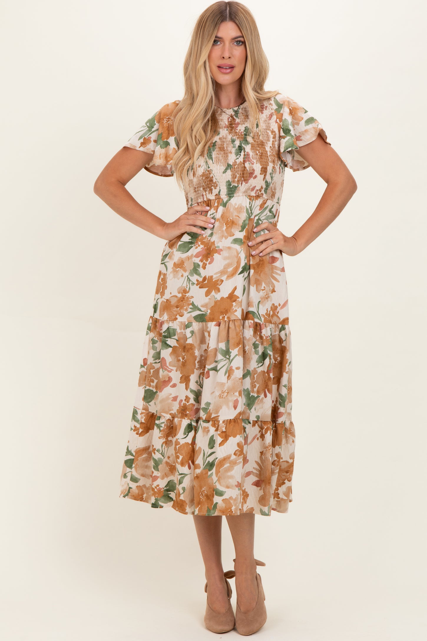 woman wearing a floral midi dress with short sleeves and a smocked bodice, styled with beige heels