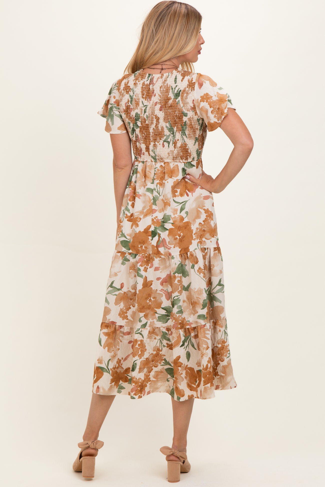 woman wearing a back view of a floral midi dress with brown and orange flowers and ruffled sleeves