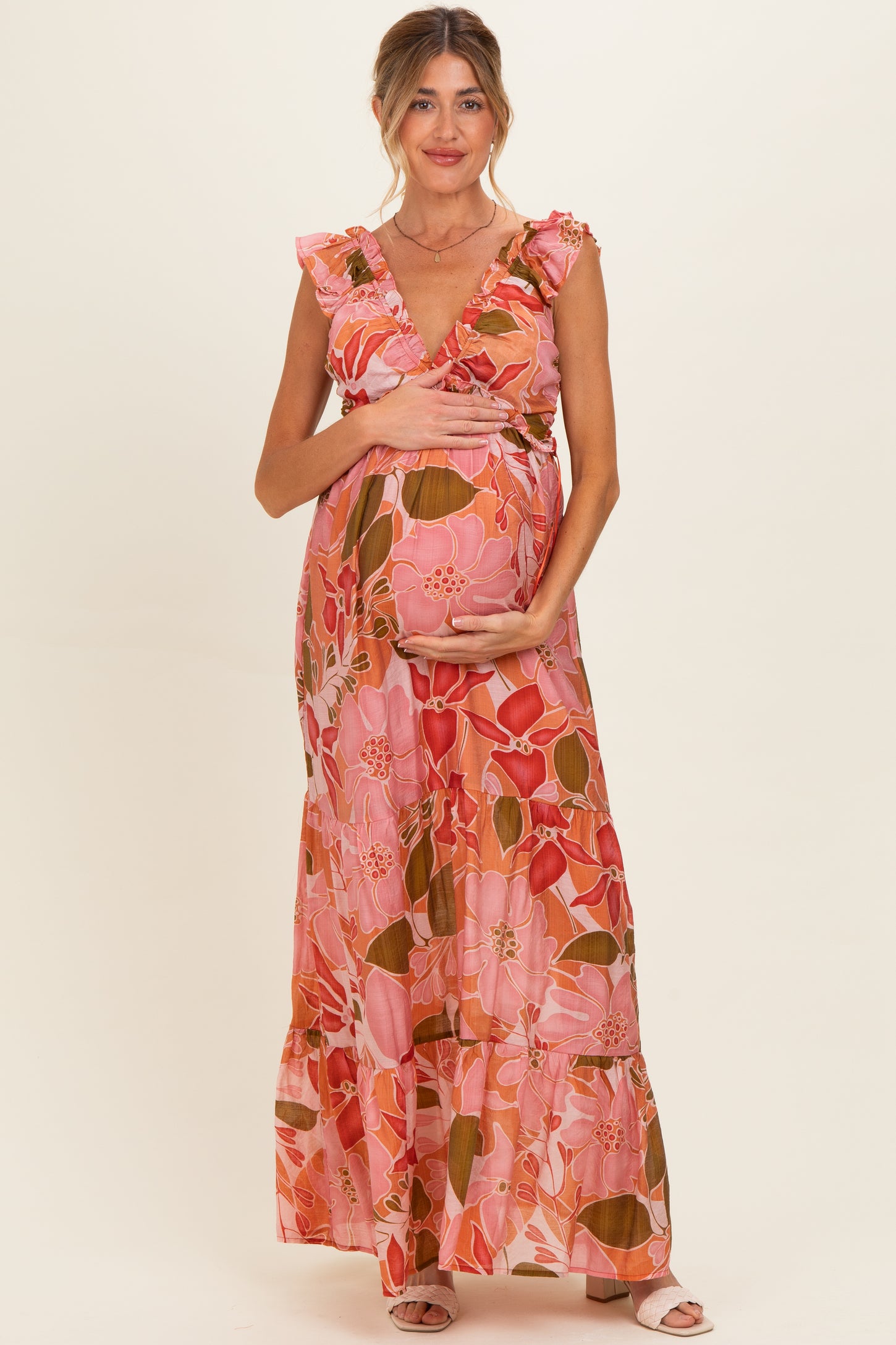 woman wearing a pink floral maternity maxi dress and holding her baby bump