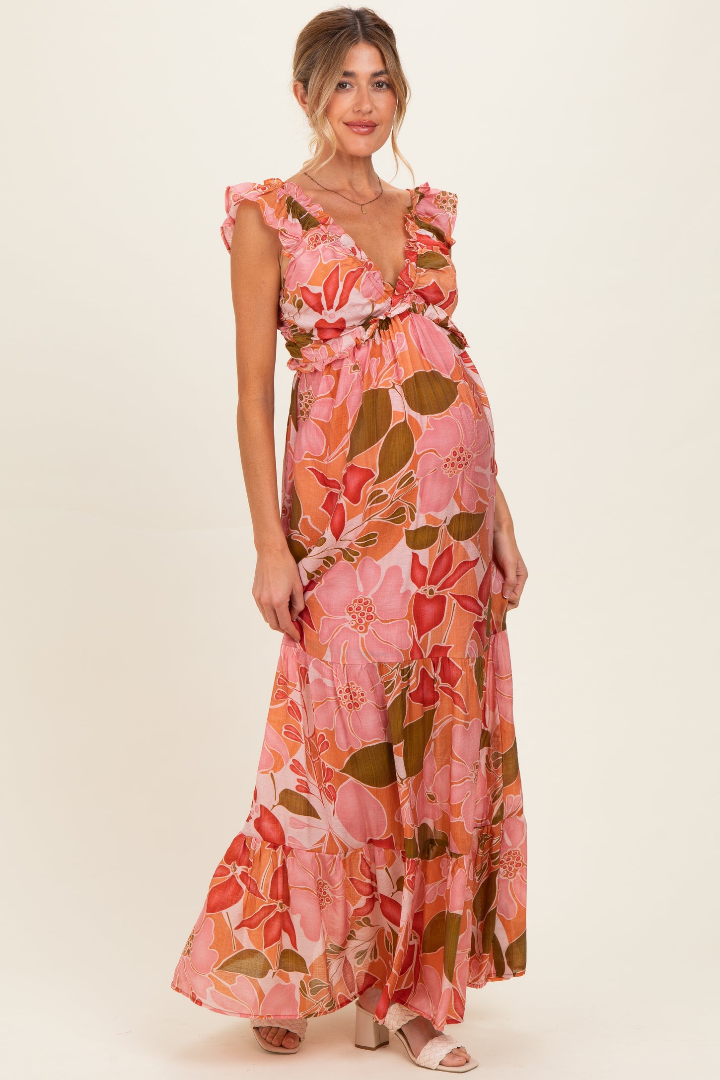 woman wearing a pink floral maternity maxi dress with ruffled sleeves and a baby bump visible