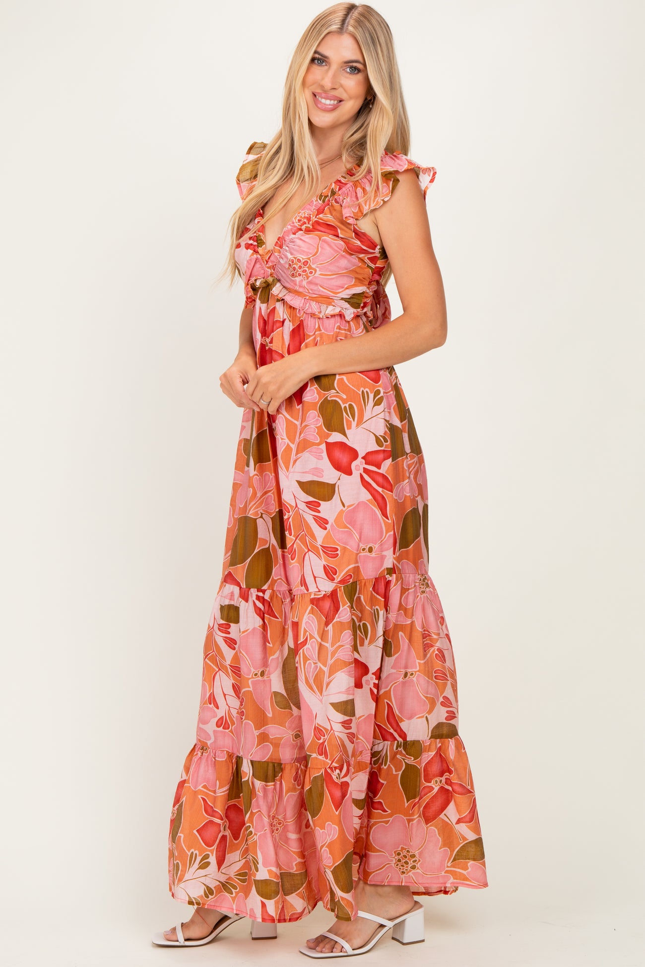 woman wearing a pink floral maxi dress with ruffle sleeves and a tiered skirt