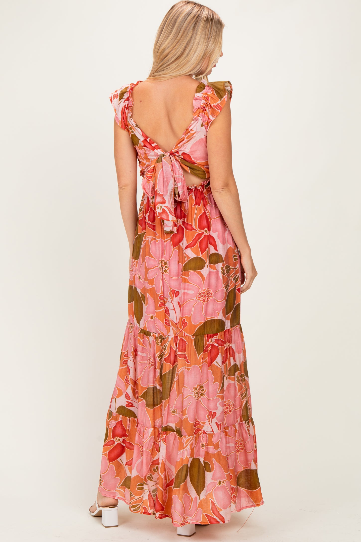 woman wearing a pink floral maxi dress with ruffled sleeves and a tie back detail