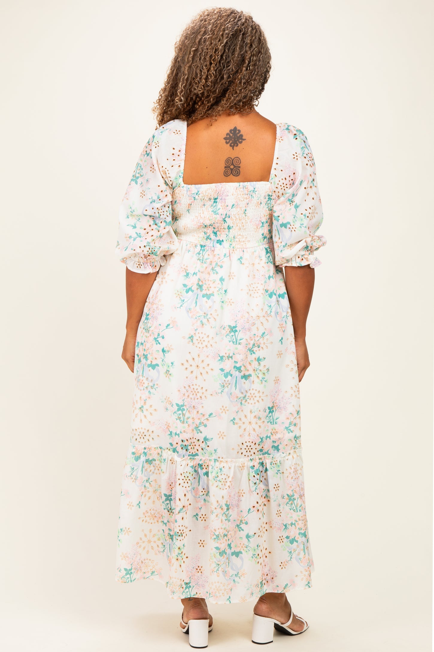 woman wearing a floral print plus size maxi dress with a smocked back and puff sleeves, showing a tattoo on her back