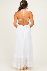 woman wearing a white halter neck maternity maxi dress with tiered ruffle hem and open back design