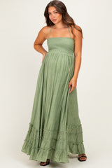 woman wearing a green maternity maxi dress with a smocked bodice and tiered ruffle hem, showing her baby bump