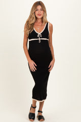woman wearing a black maternity dress with white trim and a tie neckline, showing her baby bump