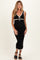 woman wearing a black maternity dress with white trim and a tie neckline, showing her baby bump
