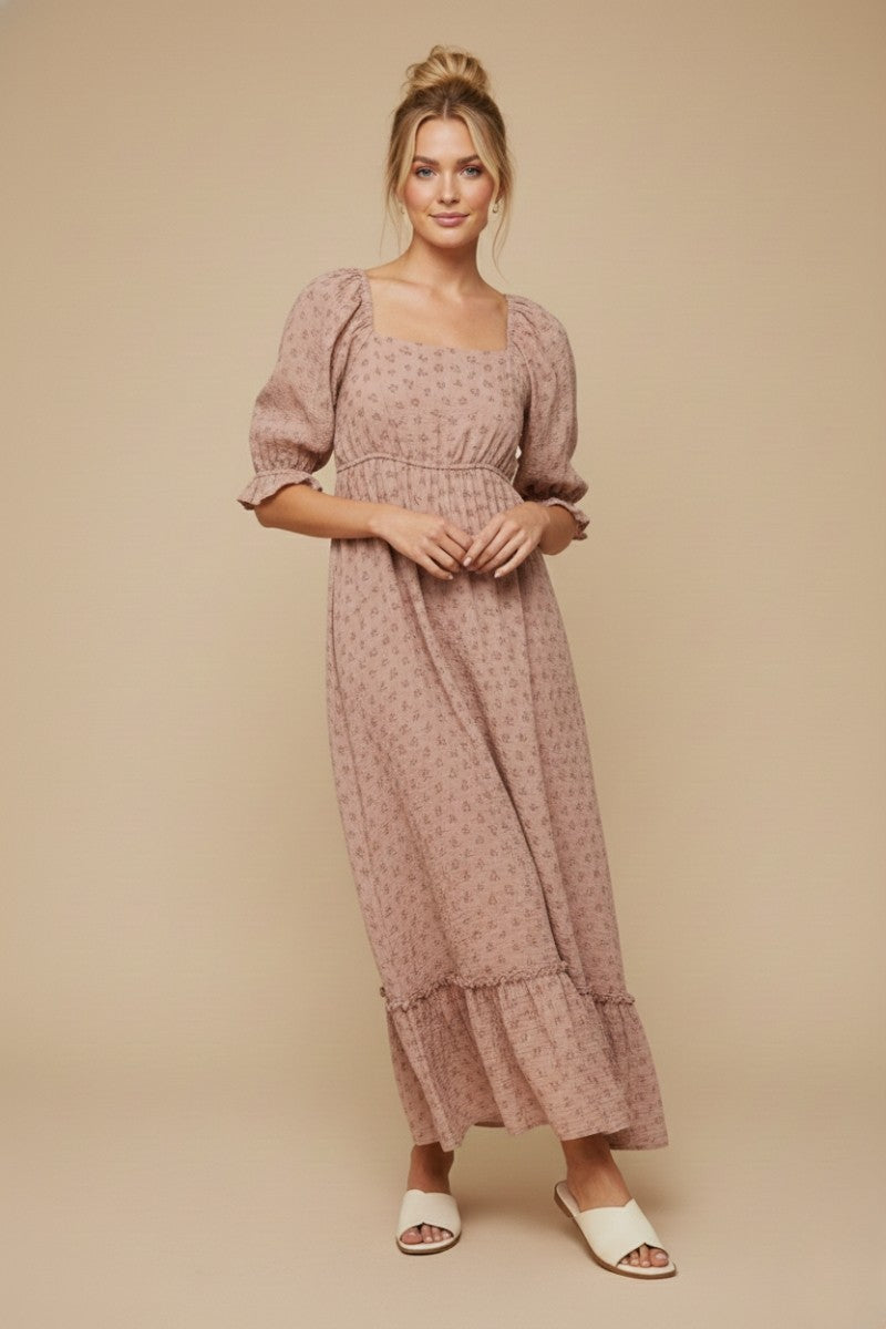 woman wearing a pink floral maxi dress with puff sleeves and ruffle hem, standing against a neutral background