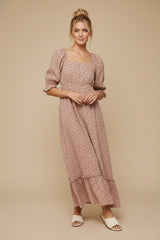 woman wearing a pink floral maxi dress with puff sleeves and ruffle hem, standing against a neutral background