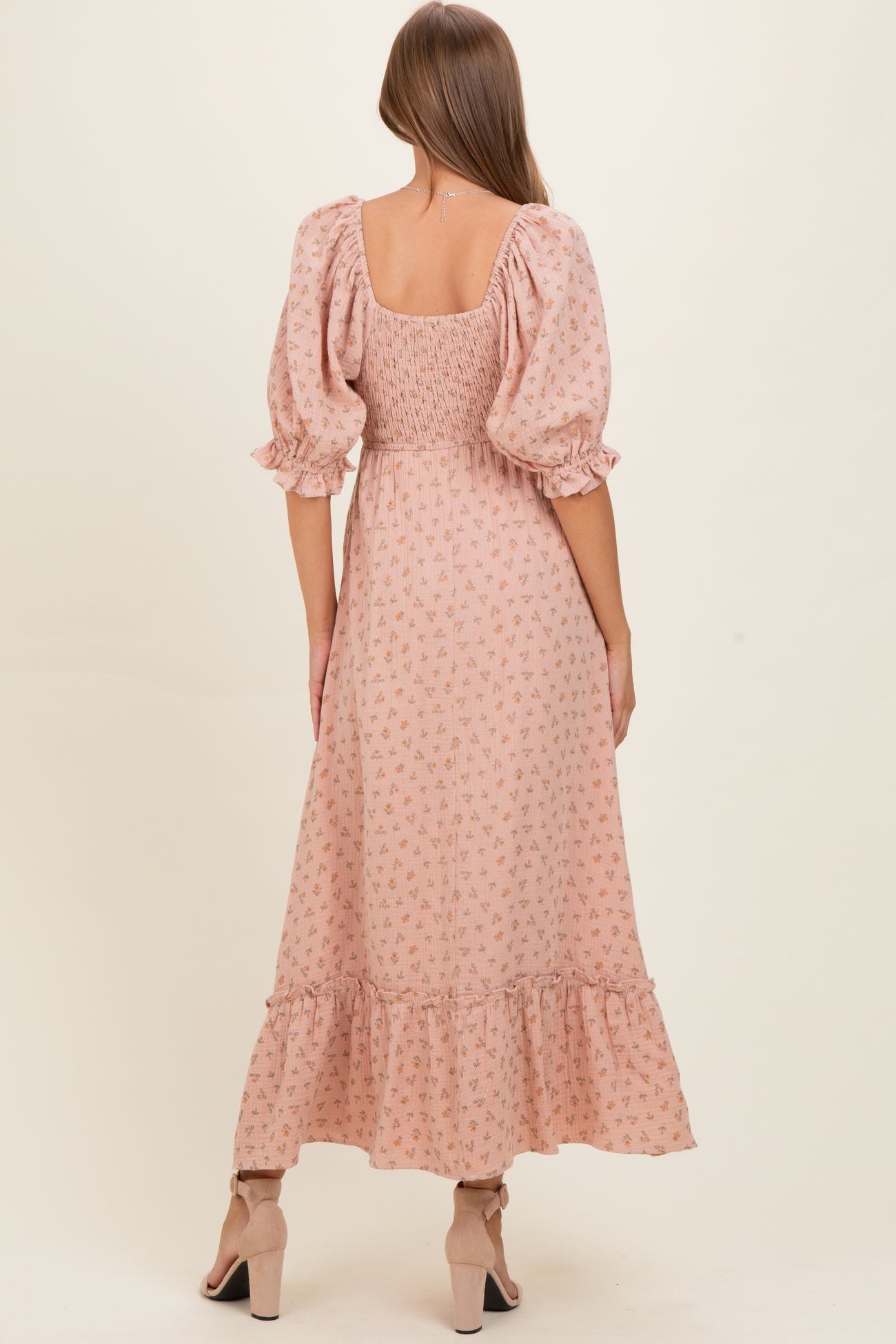 woman wearing a pink floral maternity dress with puff sleeves and a tiered ruffle hem