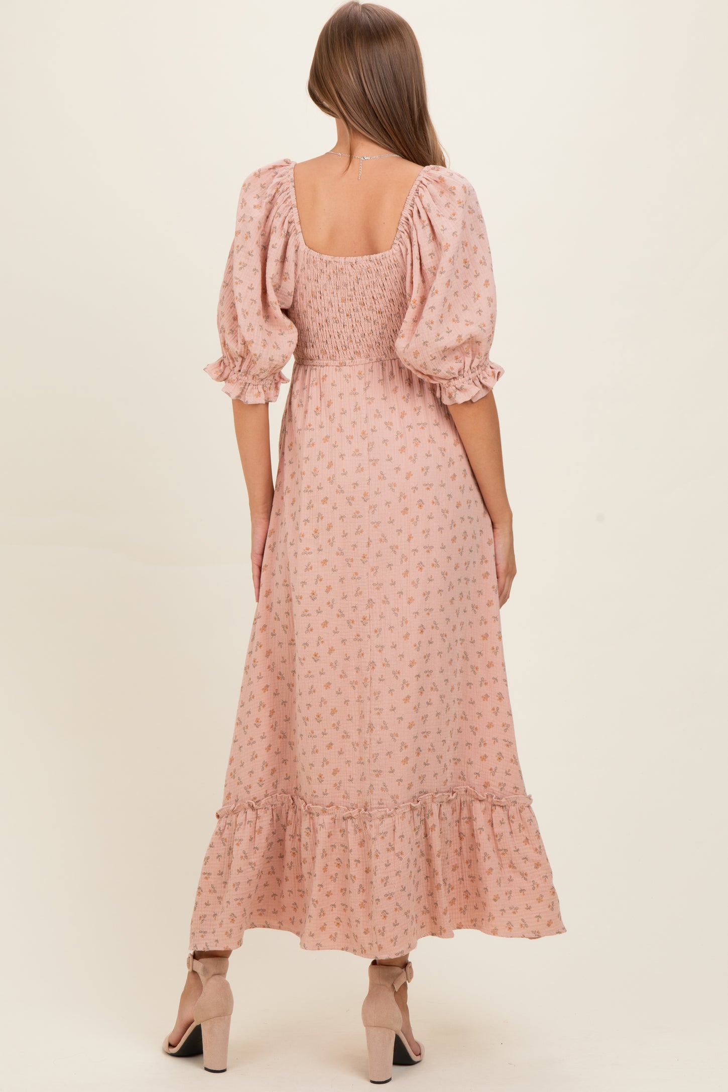woman wearing a pink floral maternity dress with puff sleeves and a tiered ruffle hem