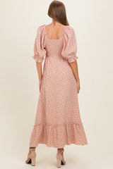 woman wearing a pink floral maternity dress with puff sleeves and a tiered ruffle hem