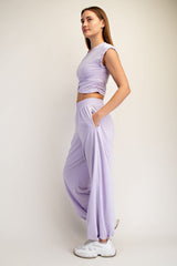 woman wearing a lavender cropped ruched top and matching loose-fit jogger pants with side pockets