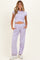 woman wearing a lavender cropped maternity top and matching loose-fit maternity pants, showing her baby bump
