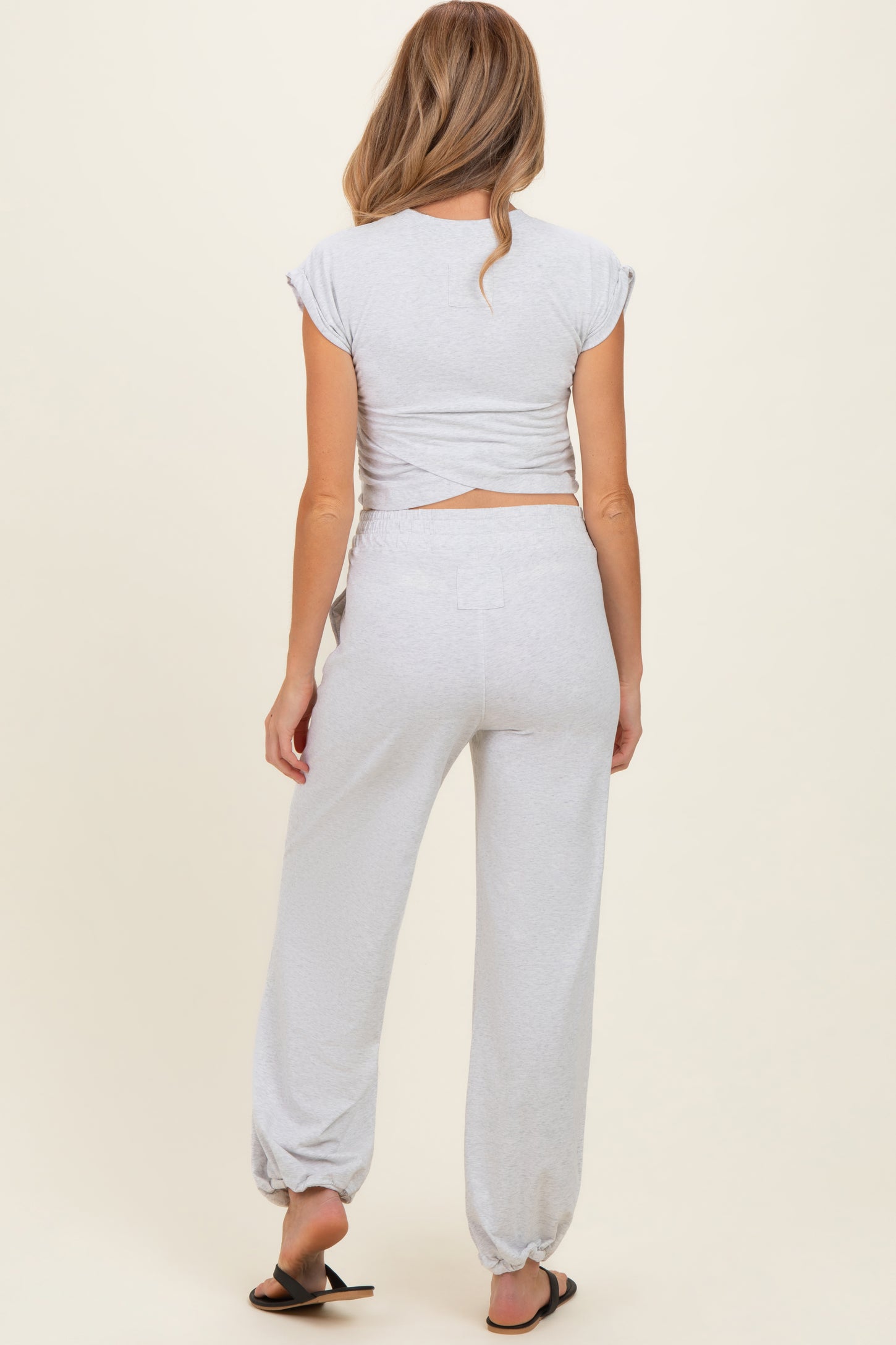 woman wearing a grey maternity crop top with crisscross back and matching jogger pants