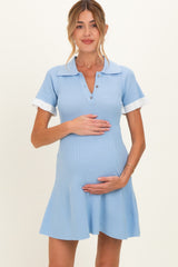 woman wearing a light blue maternity dress with a polo collar and short sleeves, holding her baby bump