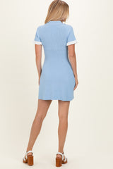 woman wearing a light blue short sleeve sweater dress with white collar and cuffs, standing with back to the camera