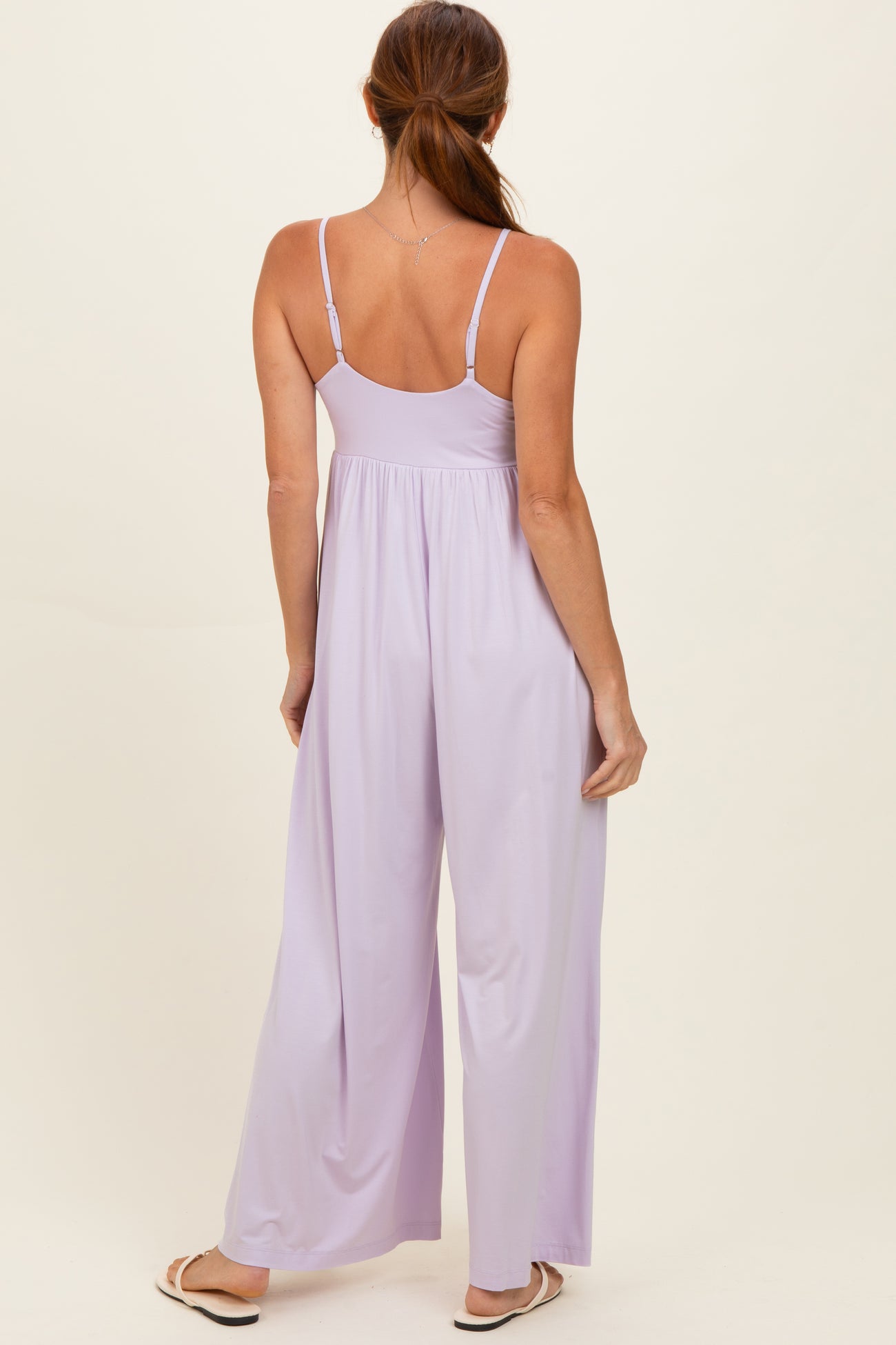 woman wearing a light purple sleeveless jumpsuit with a flowy wide leg design, shown from the back