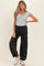 woman wearing a gray maternity henley top and black loose-fit maternity pants with pockets