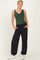 woman wearing a dark green sleeveless bodysuit and black comfy jogger pants with pockets, styled with white sneakers