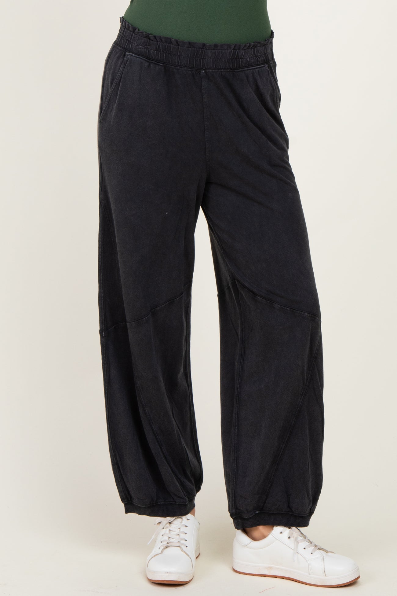 woman wearing black relaxed fit jogger pants with an elastic waistband and side pockets paired with white sneakers